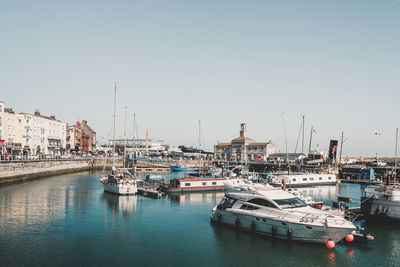 Sailboats moored at harbor against clear sky