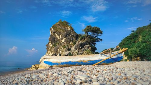 Scenic view of rocks on beach against blue sky