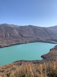 Scenic view of lake and mountains against clear blue sky