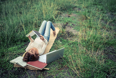 Young woman lying on book in field