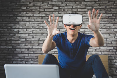 Smiling man gesturing while using virtual reality simulator at home