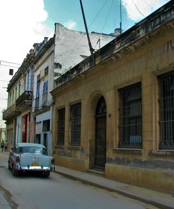 Cars on street in city against sky