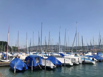 Sailboats moored at harbor against clear blue sky