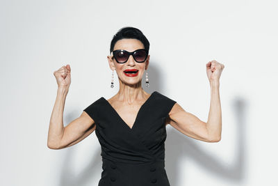 Portrait of young woman wearing sunglasses against white background