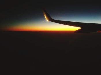 Airplane wing against sky during sunset