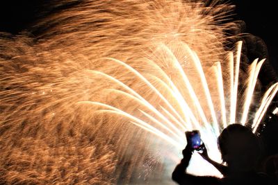 Rear view of silhouette man with fire crackers at night