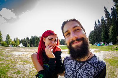 Portrait of smiling young couple against sky