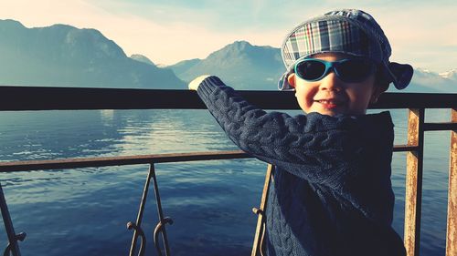 Portrait of boy standing by railing against lake