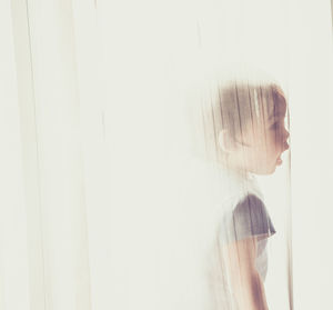 Side view of woman standing against white wall