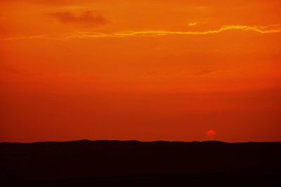 Scenic view of silhouette desert against orange sky