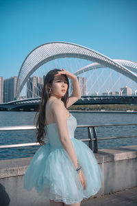 Portrait of young woman standing against river