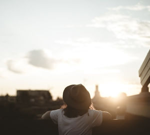 Rear view of woman standing against sky during sunset
