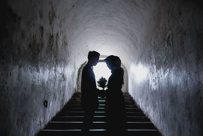 Side view of silhouette couple holding bouquet while standing on staircase