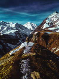 Person walking on snowcapped mountain against sky