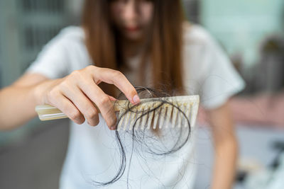 Asian woman have problem with long hair loss attach to comb brush.