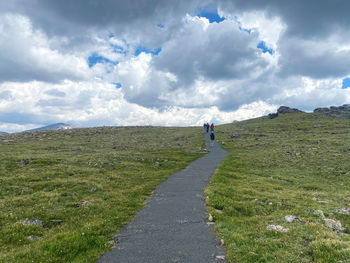 Rear view of man walking on field against sky