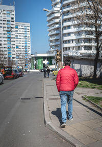 Rear view of person walking on road against buildings