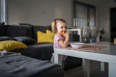 Young woman using mobile phone while sitting on sofa at home