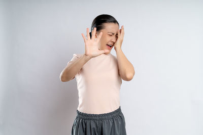 Portrait of young woman standing against white background