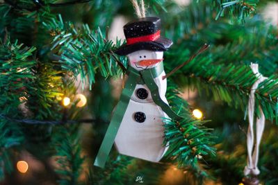 Close-up of snowman hanging on illuminated christmas tree at night