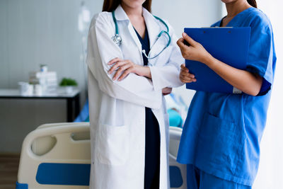 Midsection of nurse and female doctor standing in hospital ward