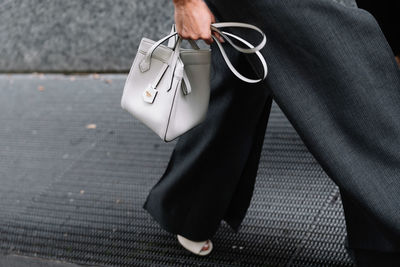 Low section of woman with bag walking on street