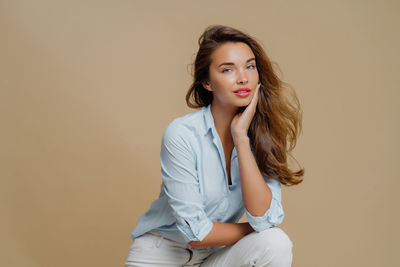 Portrait of smiling young woman standing against wall