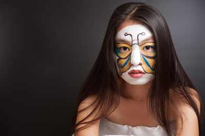 Portrait of beautiful young woman wearing mask against black background