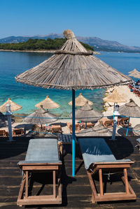 Lounge chairs and tables at beach against blue sky