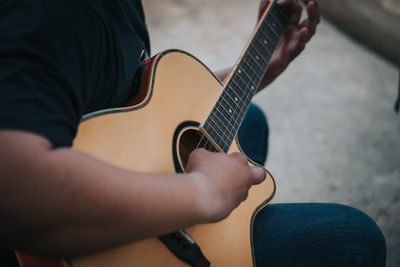 Midsection of man playing guitar