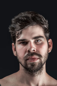 Portrait of young man against black background