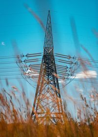 Low angle view of electricity pylon against blue sky