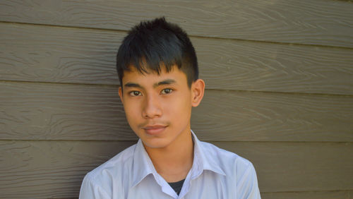 Portrait of young man standing against wall