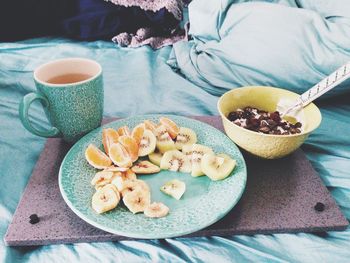 Close-up of fruit salad with coffee on bed