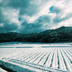 Scenic view of snowcapped landscape and mountains against cloudy sky