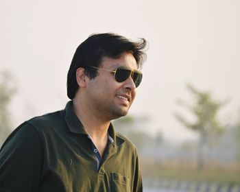 Close-up of smiling man wearing sunglasses against sky