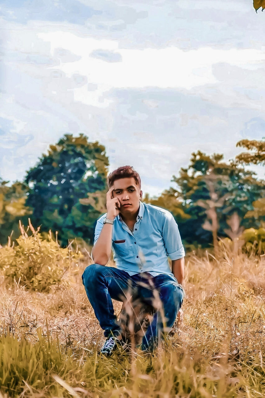 plant, real people, field, land, one person, front view, nature, growth, casual clothing, lifestyles, young men, leisure activity, sky, young adult, day, three quarter length, landscape, men, outdoors