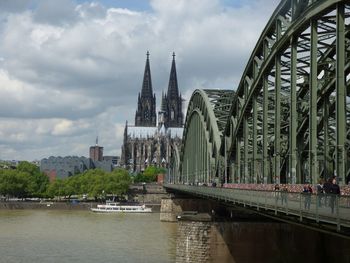 Bridge over river by buildings against sky