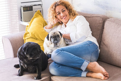 Smiling woman lying down with dogs on sofa