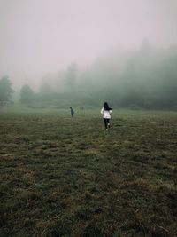 Rear view of people on field against sky