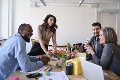 Multi-ethnic engineers smiling while working on project at table in office