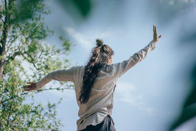 Rear view of woman with arms outstretched against sky