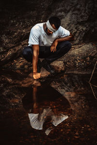 Full length of man with blindfold crouching by river