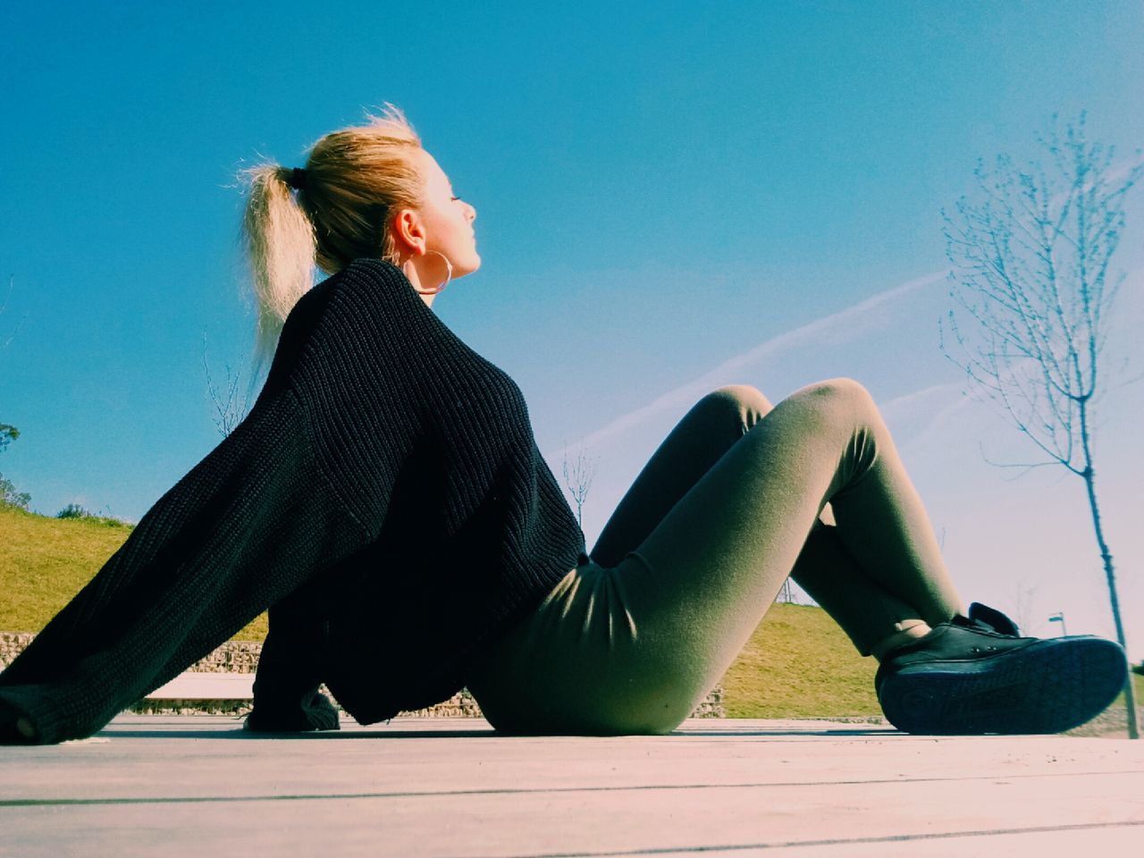 one person, blond hair, real people, full length, sitting, young adult, young women, lifestyles, casual clothing, leisure activity, side view, beautiful woman, day, outdoors, clear sky, blue, relaxation, sky, people