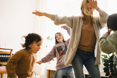 Happy woman dancing and enjoying with children at home