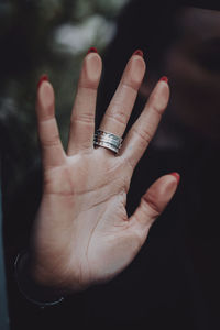 Female hand with a silver ring touching glass