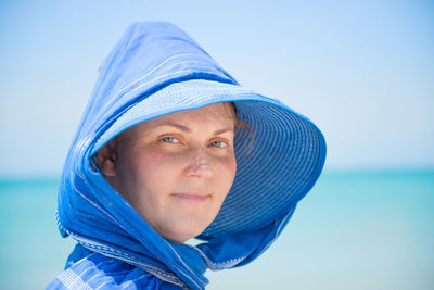 Close-up portrait of woman against blue sea against sky
