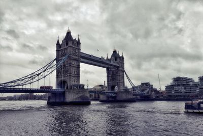 London bridge over thames river against cloudy sky