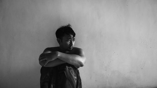 Portrait of young man standing against wall