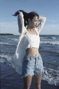 Portrait of young woman standing at beach